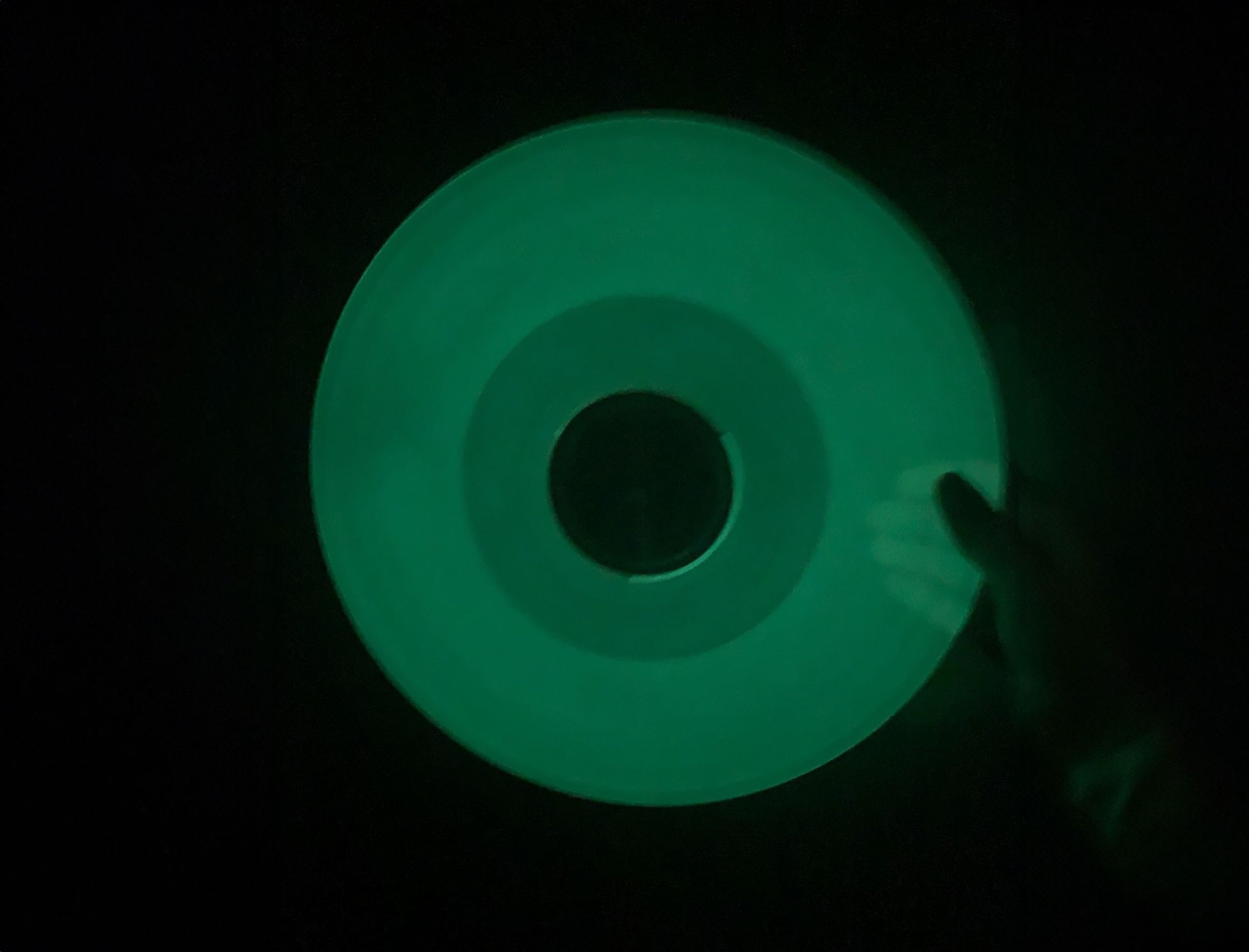 Green glow-in-the-dark vinyl record photographed in low light