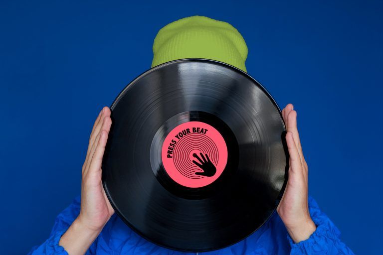 Young man in 90s style jacket holding vinyl record over face